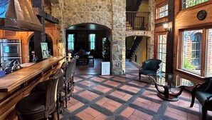 Un interior espacioso con pared de piedra, techo de madera y una zona de bar con asientos.