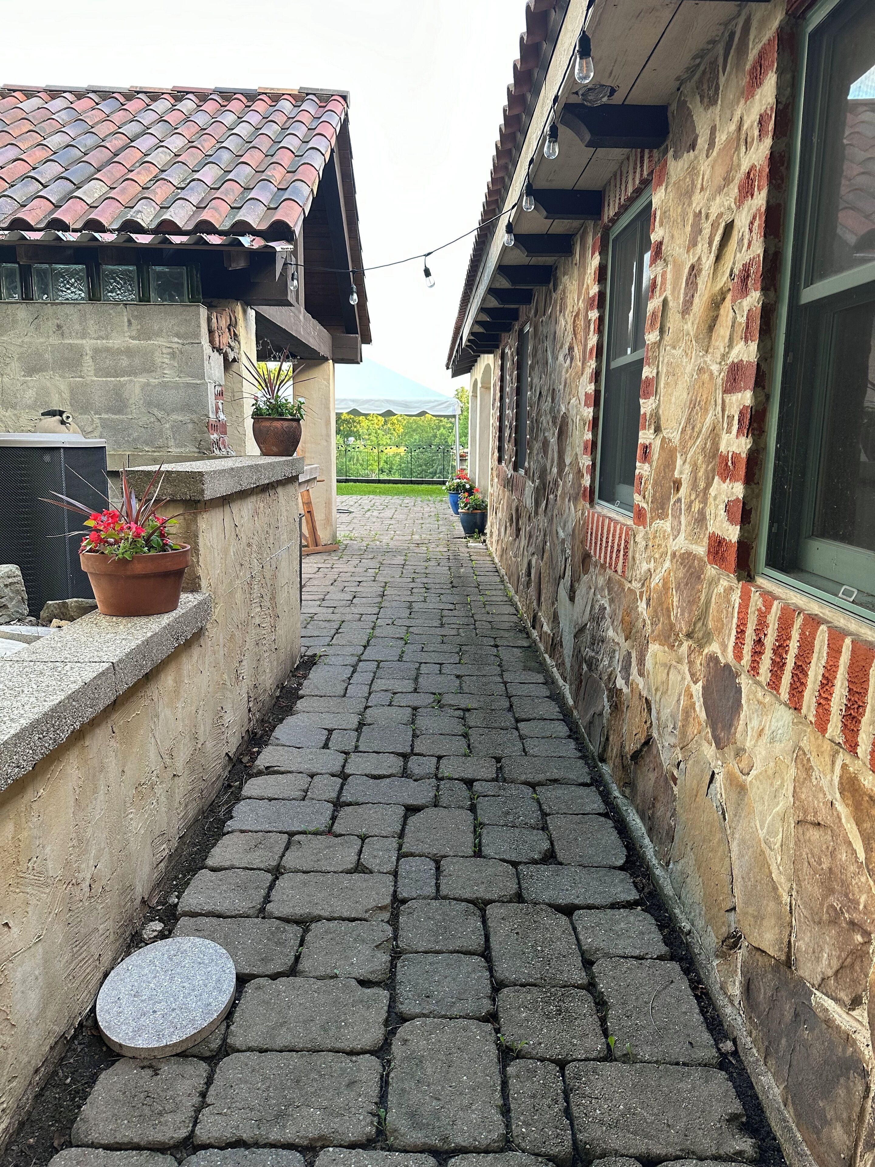Un étroit sentier pavé de pierres entre deux bâtiments, dont les toits sont recouverts de tuiles et les murs en pierre.