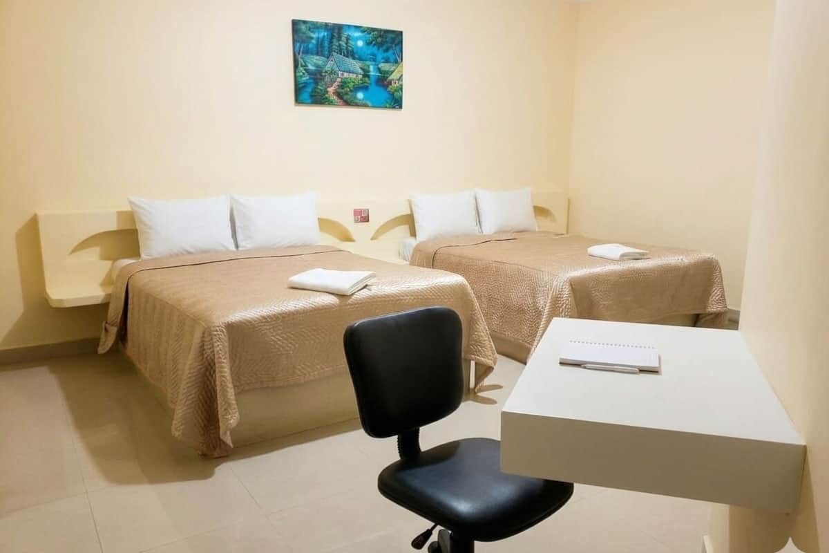 Une chambre d’hôtel avec deux lits, un bureau et une chaise.