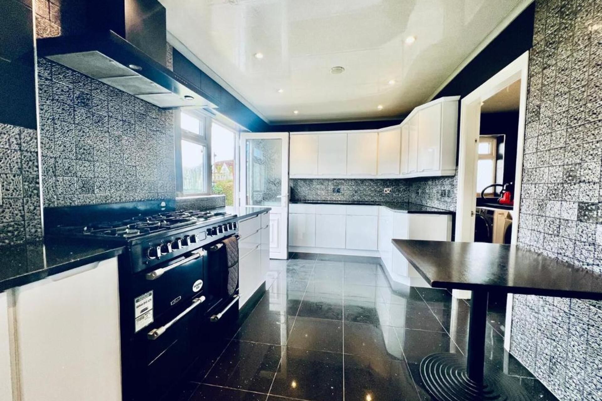 A modern kitchen with a black stove, white cabinets, and a granite countertop.