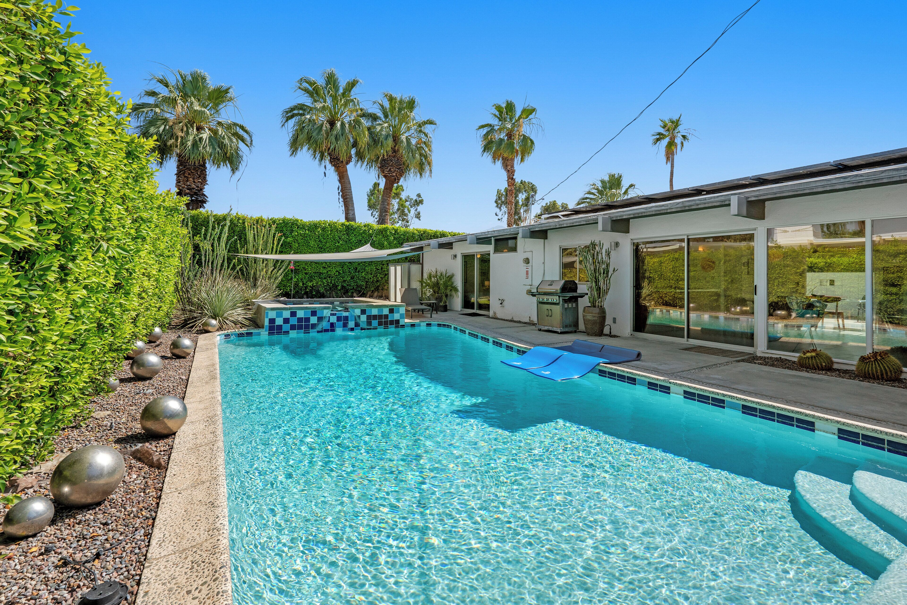 Een buitenzwembad, parasols bij het zwembad en ligstoelen