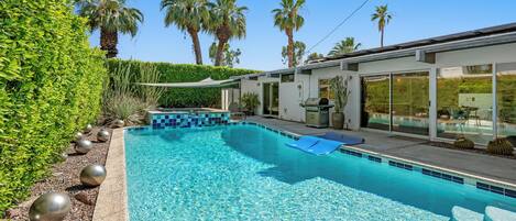 Een buitenzwembad, parasols bij het zwembad en ligstoelen