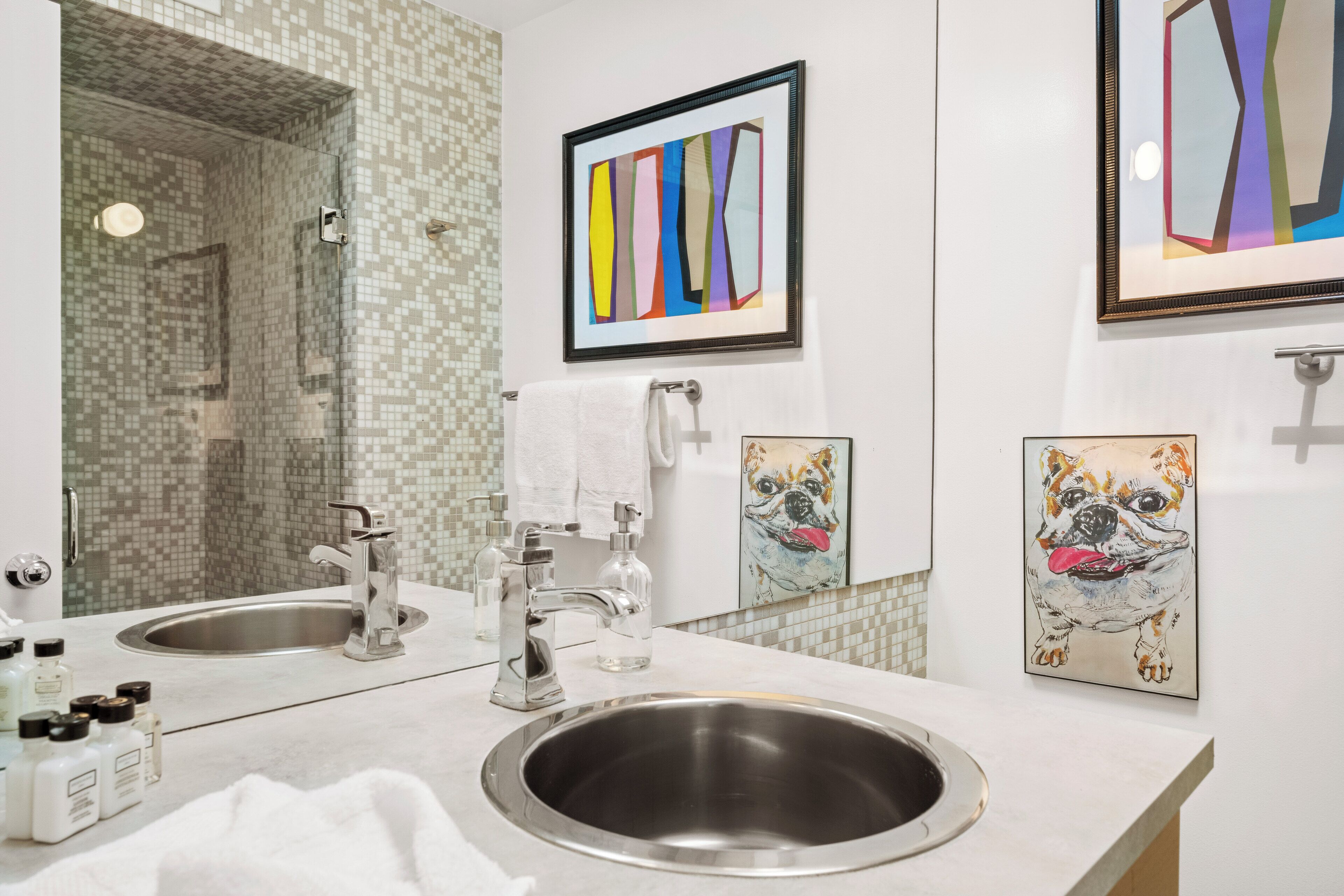 Un baño con dos lavamanos, un espejo y obras de arte enmarcadas en la pared.