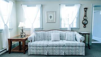 A room with a sofa, a table, and a clock on the wall.