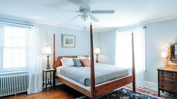 A four-poster bed with a wooden frame, two bedside tables with lamps, a radiator, and a patterned rug.
