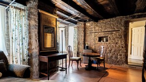 Une pièce rustique aux murs de pierre, avec une table en bois et un grand miroir.
