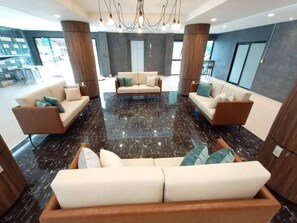 A modern lobby with a central seating area, large pillars, and a chandelier.