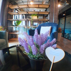 Un intérieur moderne avec un fauteuil bleu, une table sur laquelle est posée une plante de lavande en pot, et un panneau en forme de cœur indiquant la disponibilité du Wi-Fi.
