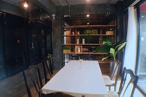 A dining area with a long table, chairs, and a bookshelf in the background. - Modern Budget Hotel (Hat Yai)