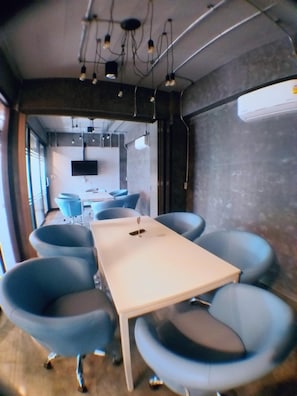 A conference room with a long table, blue chairs, and pendant lighting.