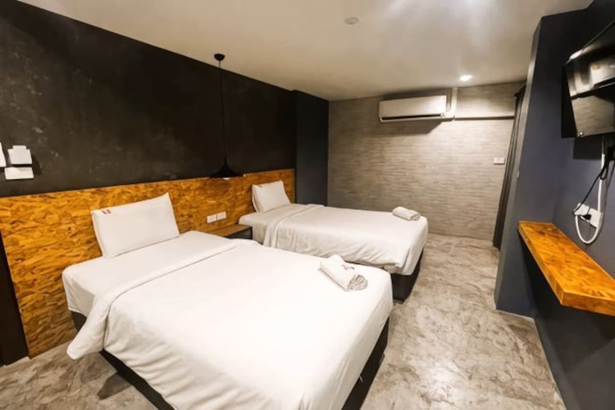 A hotel room with two beds, a wooden headboard, a marble floor, a wooden shelf, and an air conditioning unit.
