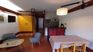 Um espaço compacto com área de jantar, cozinha compacta e pequeno espaço para sentar.