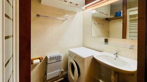 Casa de banho compacta com máquina de lavar roupa, pia e espelho.