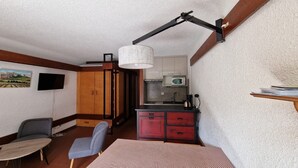 Quarto compacto com cozinha compacta, área de refeições com mesa e cadeiras, e uma cama.