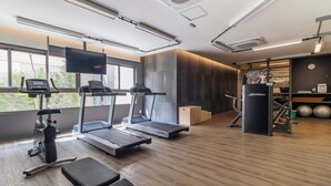 Une salle de sport moderne équipée de tapis de course, d’un vélo d’appartement et de matériel de musculation.