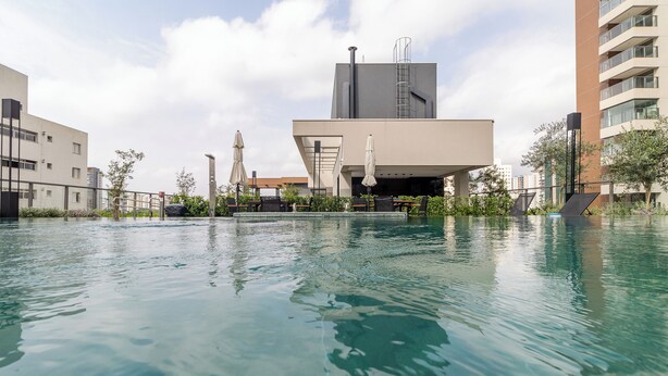 Un bâtiment moderne doté d’un espace piscine, comprenant des chaises longues et des parasols.
