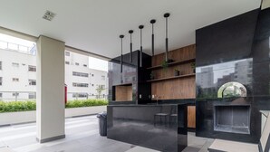 Un espace intérieur moderne doté d’un comptoir en marbre noir, d’étagères en bois, de luminaires suspendus et offrant une vue sur un bâtiment à l’extérieur.