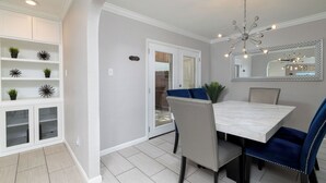 A dining area with a marble table, blue upholstered chairs, a chandelier, and a mirrored wall. - Patio + Covered Terrace - Steps to TCU (Fort Worth)