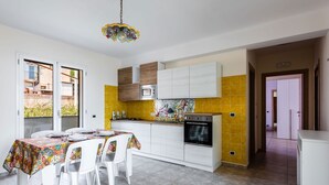 Una cucina moderna con mobili bianchi, uno schienale giallo e un'area pranzo con una tovaglia colorata.