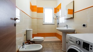 Un bagno piccolo ma funzionale, con il water, bidet, lavandino e lavatrice.