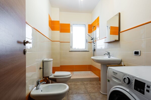A compact bathroom with a toilet, bidet, sink, and washing machine. - Casa Sirina by Wonderful Italy (Giardini Naxos)