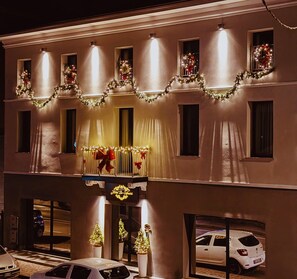 A hotel facade with multiple windows, some adorned with Christmas decorations. - HOTEL DE AMICIS  (Moglia)