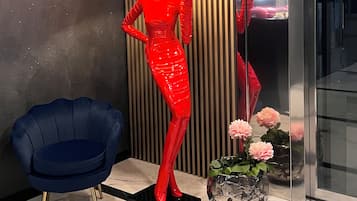A modern interior with a blue chair, a red sculpture, and a vase with flowers.