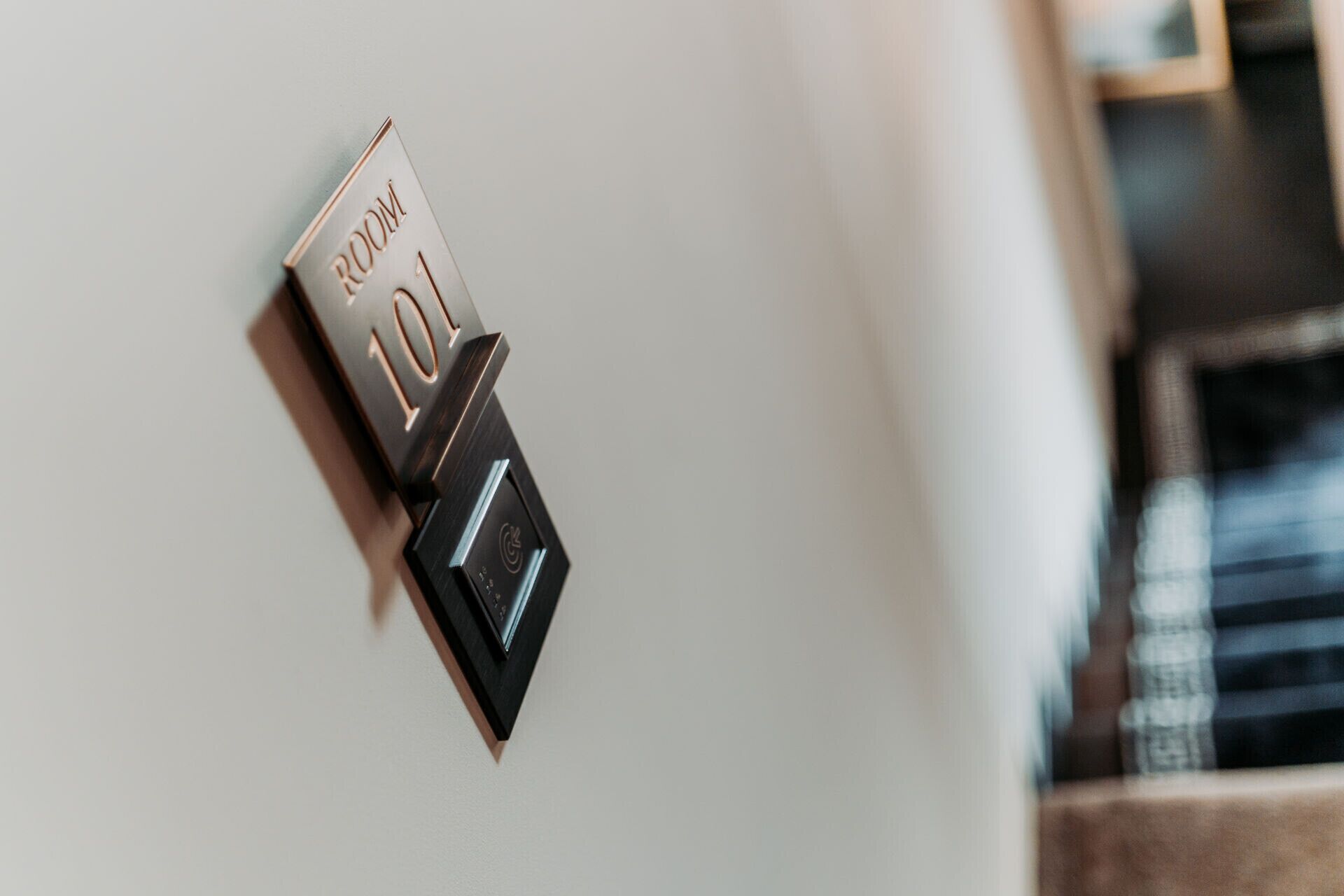 A door with a room number plaque, a keycard reader, and a door handle.