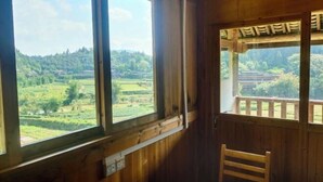 A room with wooden walls and large windows offering a view of a green landscape. - Sanjiang Panjin Farmhouse (Sanjiang)