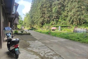 Un chemin pavé mène à un bâtiment devant lequel est garé un scooter.