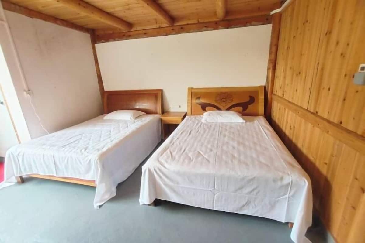 A room with two single beds, wooden walls, and a simple, clean design.