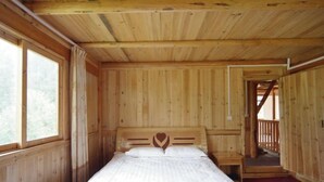 A wooden cabin room with a bed, a small table, and a window. - Sanjiang Panjin Farmhouse (Sanjiang)