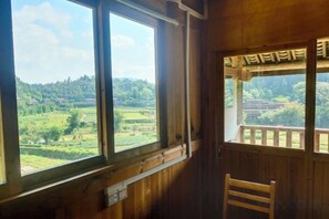 Ein Zimmer mit Holzvertäfelung, einem Fenster mit Blick auf eine grüne Landschaft und einem Sessel.