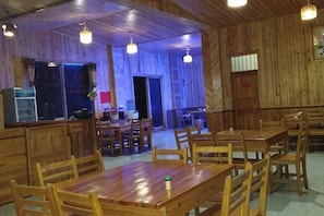 A wooden interior with tables and chairs, a counter, and hanging lights. - Sanjiang Panjin Farmhouse (Sanjiang)