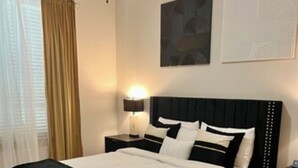 A modern bedroom with a large bed, a bedside table with a lamp, and a large window with curtains. -  New! Luxury Midtown Escape (Houston)