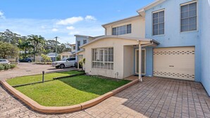 A two-story residential building with a garage, a well-maintained lawn, and a paved driveway. - Pier 8 by Experience Jervis Bay (Huskisson)