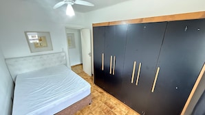 Un dormitorio con cama, armario, ventilador de techo y puerta.