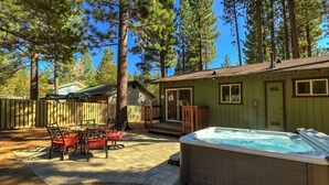 Un jardin avec un jacuzzi, une terrasse en bois et un petit bâtiment doté de fenêtres.