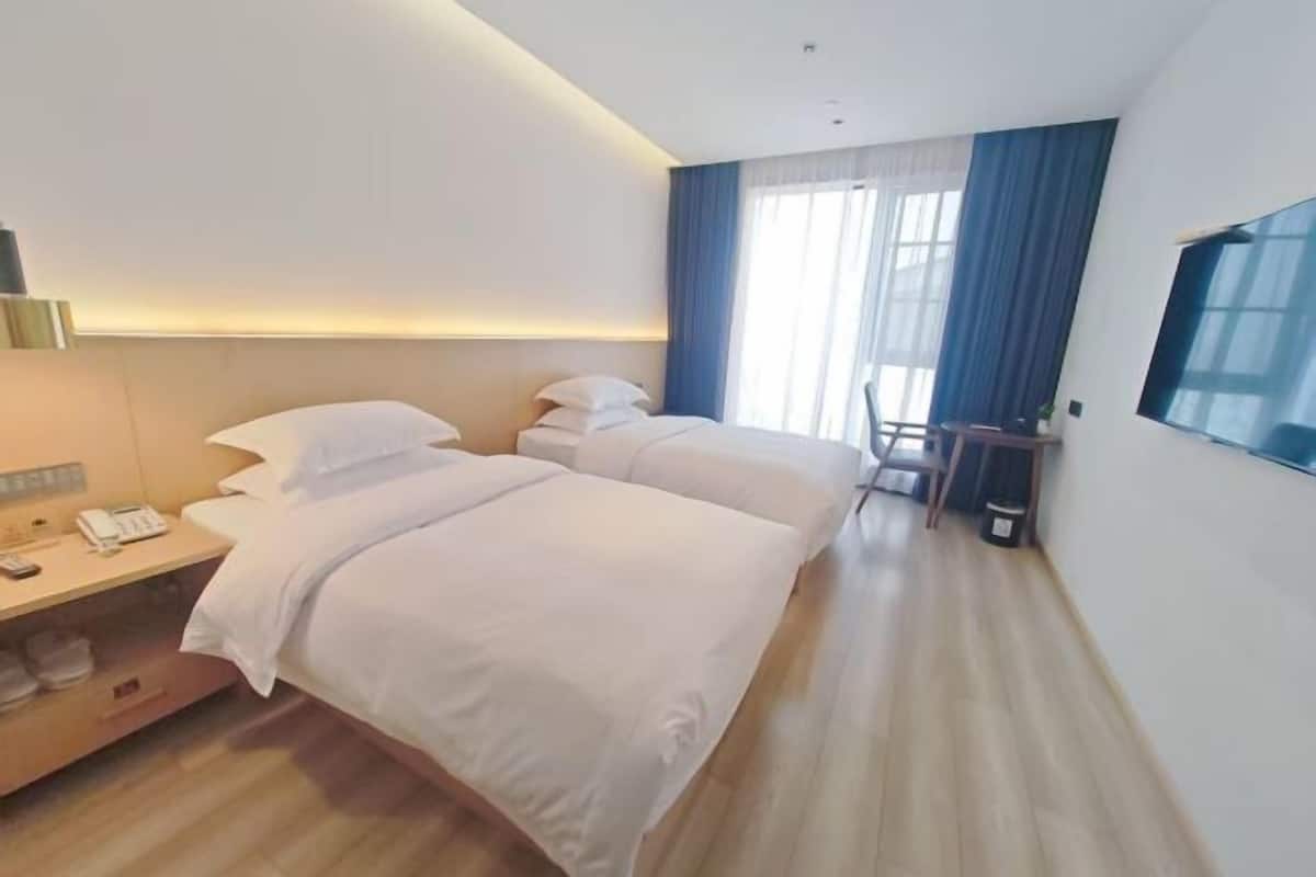 A hotel room with two beds, a desk with a phone, and a chair.