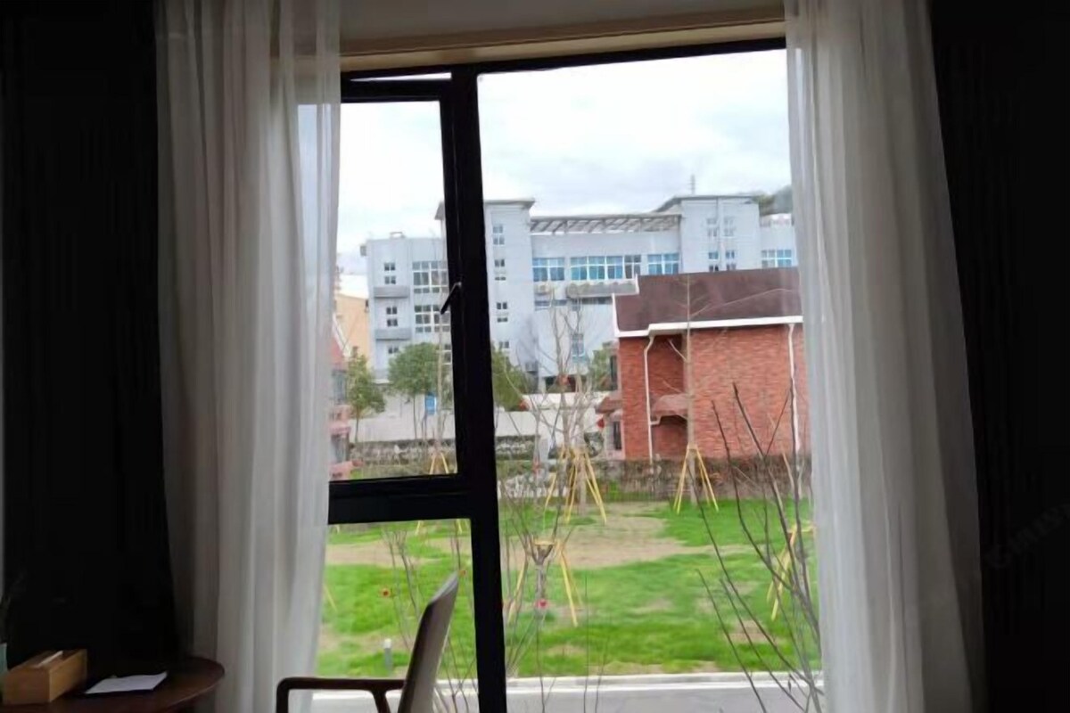 A room with a large window, a chair, and a small table.