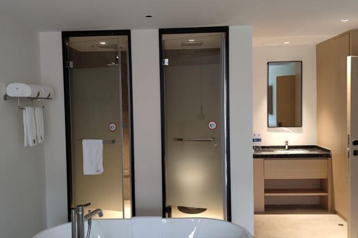 A modern bathroom with a large white sink, a glass-enclosed shower, and a mirror above the sink.