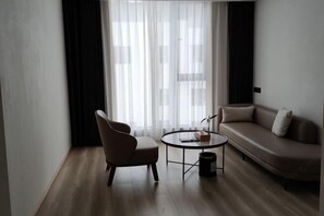 A modern living room with a sofa, a chair, a small round table, and a large window with sheer curtains. - Ruian Zhailiaoxi Hotel (Rui'an)