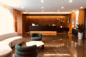 Un área de recepción moderna con mostrador, asientos y suelo pulido.