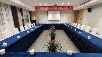 A conference room with a long table, white chairs, and a blue tablecloth.