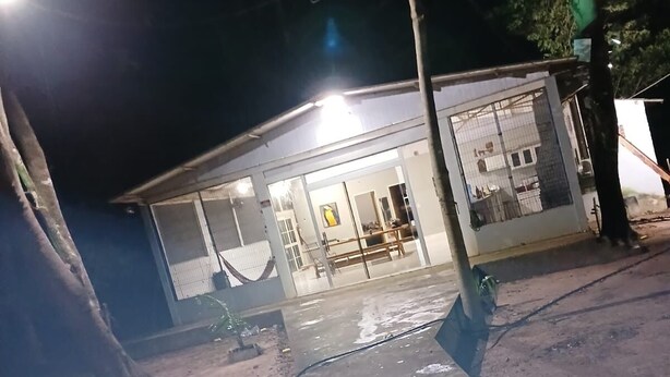 Een gebouw met een glazen gevel, een duidelijke deur en een bank ervoor.