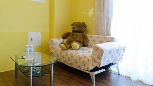 Ein Zimmer mit Glastisch, floralem Sofa und einem großen Teddybären.
