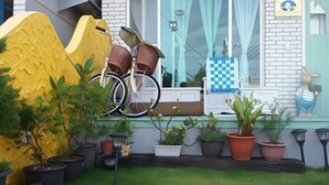 Een tuin met plantenpotten, een fiets en een raam met gordijnen.