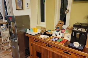 A breakfast bar with pastries, a coffee machine, and a refrigerator.