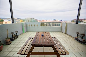 A rooftop terrace with a wooden table and chairs, potted plants, and a view of the cityscape. - Slow Travel Taitung B&B (Taitung)