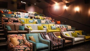Un théâtre doté de nombreuses rangées de sièges, comprenant des fauteuils et des canapés confortables, disposés en gradins.